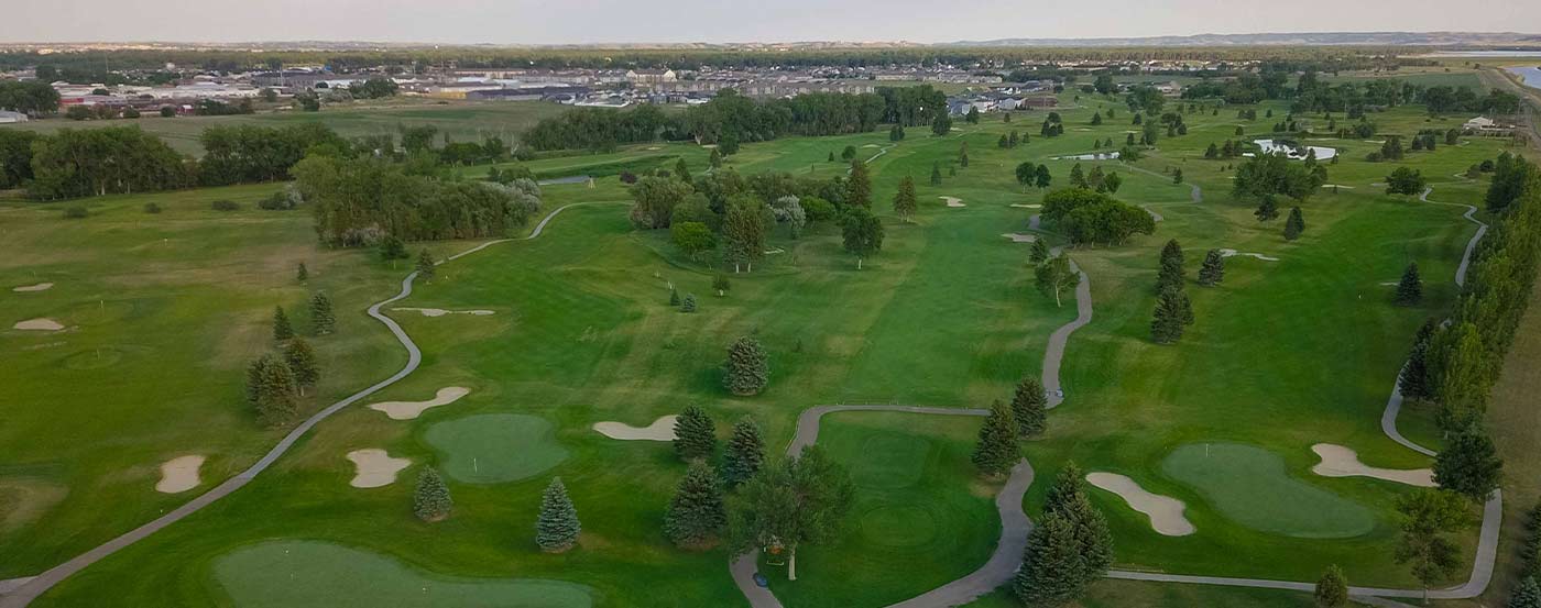 aerial view of golf course greens and housing development in the distance