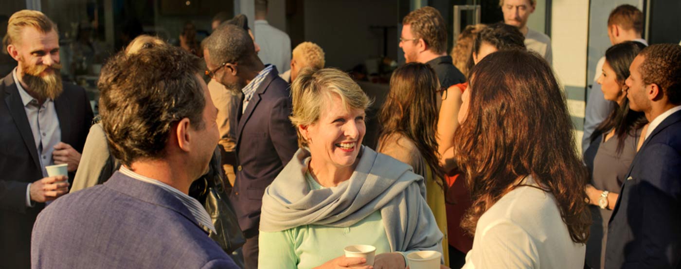 diverse group of people mingling outside in the evening